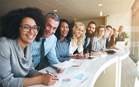 Line of people at a desk smiling.